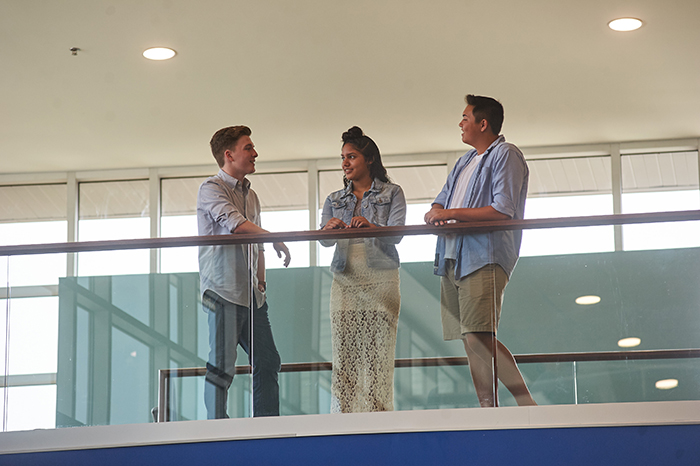 Three students talking inside campus building